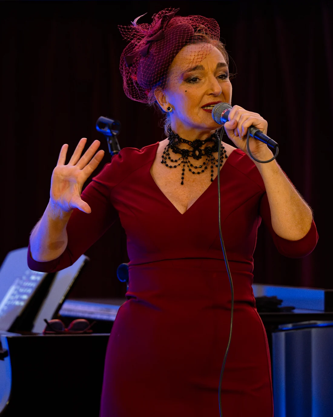 Sam Chara singing on stage in a deep red dress and headpiece